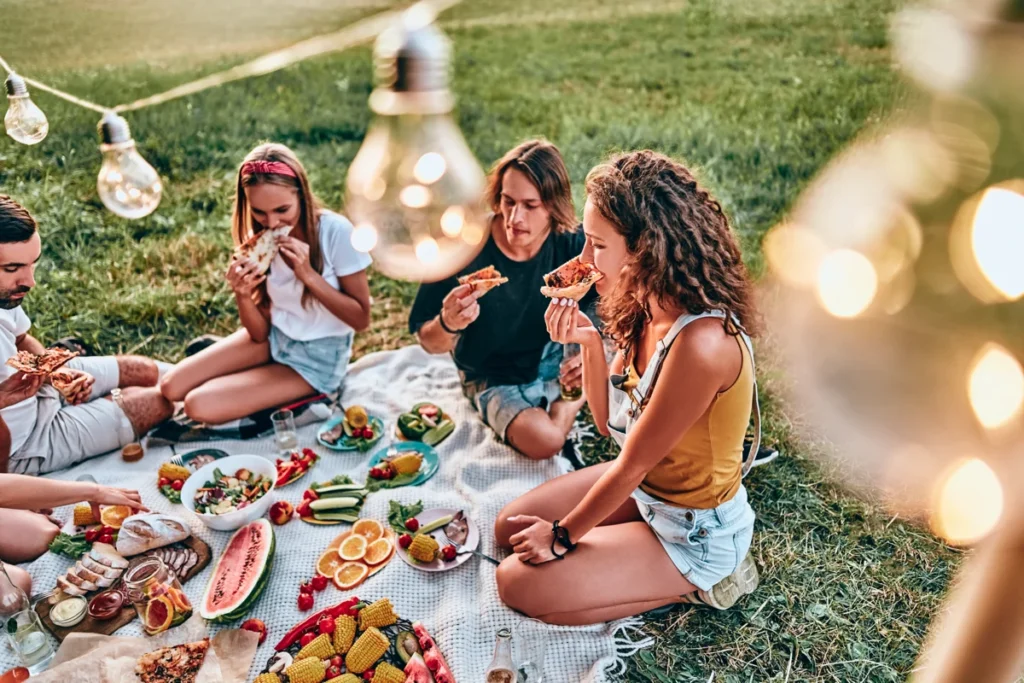 Amis pique-niquant et mangeant pizza sur l’herbe