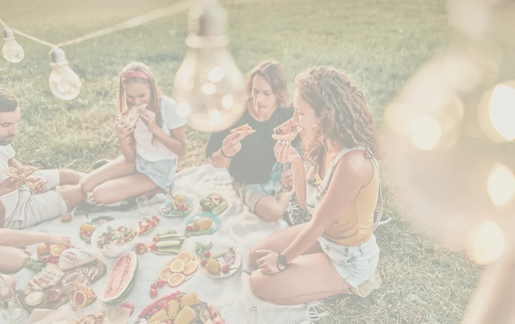 Groupe d’amis pique-niquant et mangeant pizza en plein air