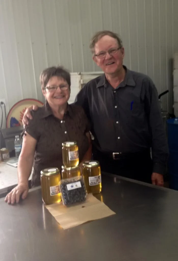 Couple souriant présentant pots de miel artisanal