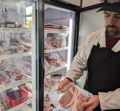 Boucher choisissant une viande en vitrine réfrigérée