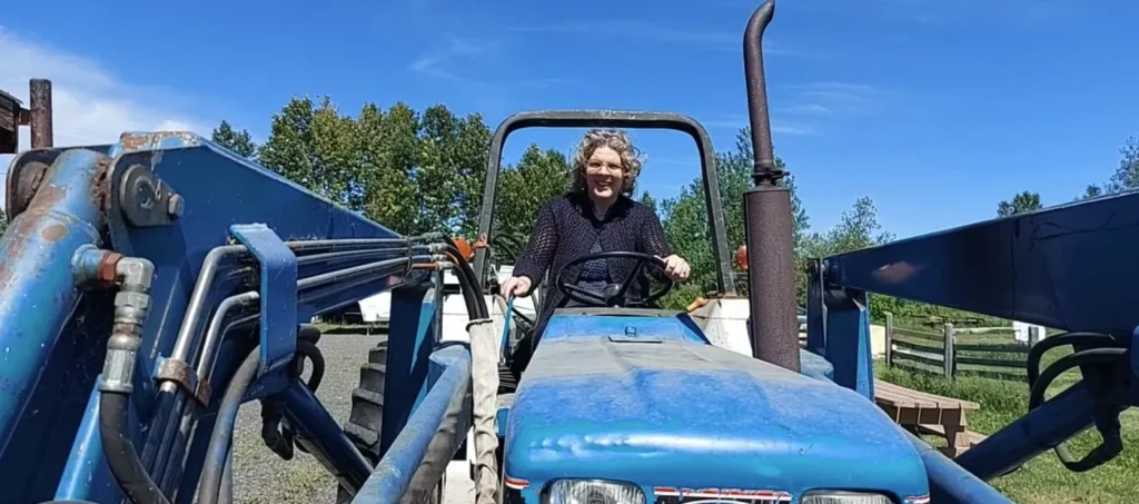 Femme souriante au volant d’un tracteur bleu