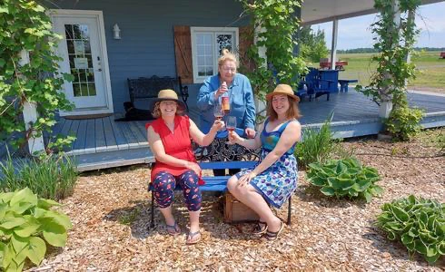 Trois femmes assises devant une maison