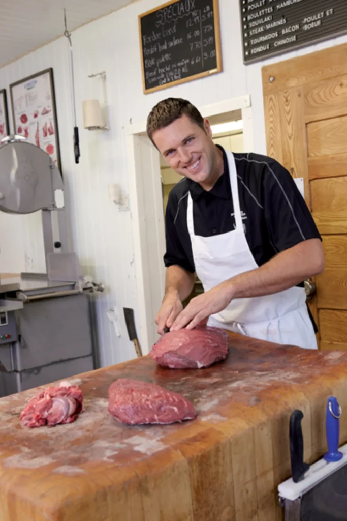 Boucher souriant préparant de la viande fraîche