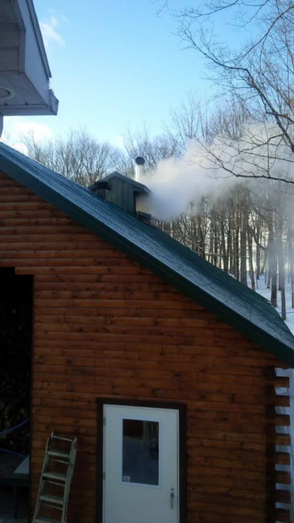 Chalet en bois avec cheminée fumante en hiver