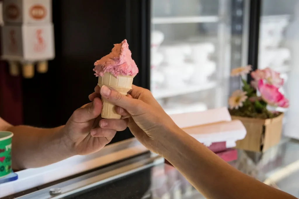 Main tendant une glace en cornet rose