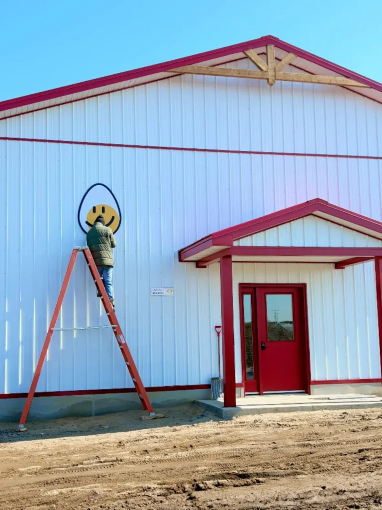 Personne peignant un smiley sur bâtiment blanc