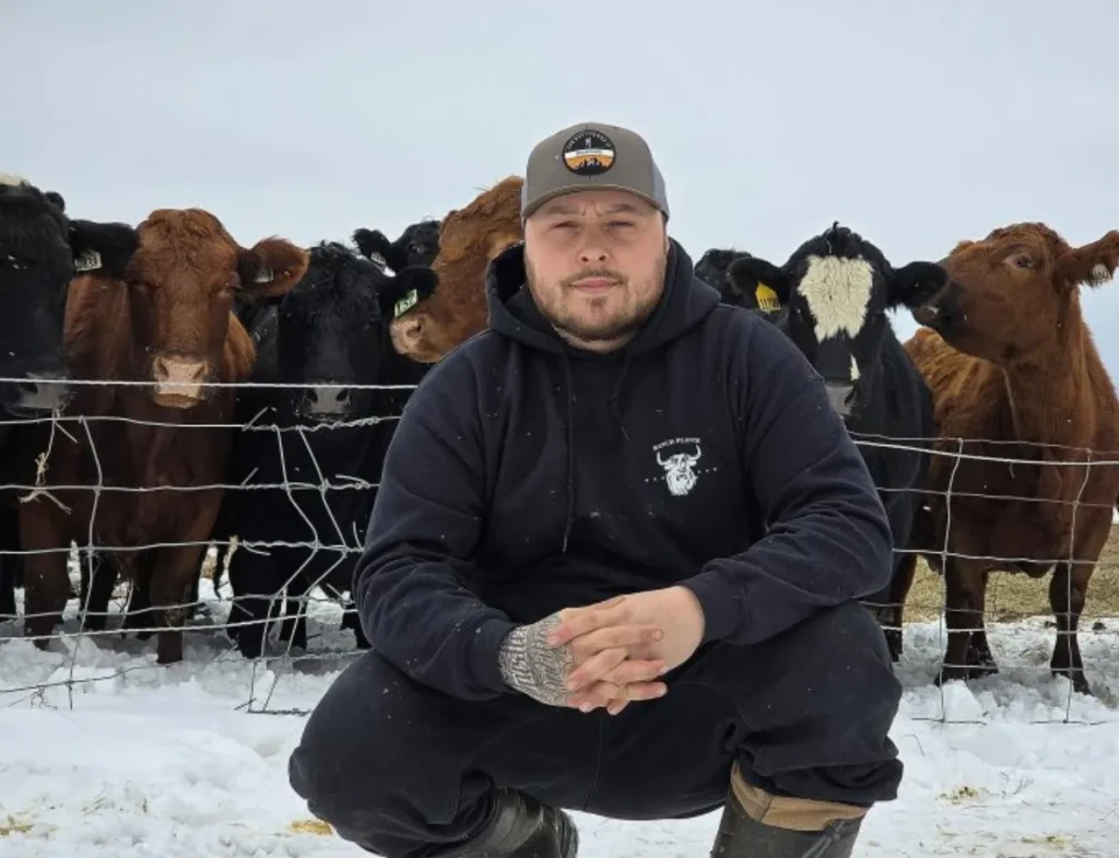 Homme accroupi devant des vaches dans la neige