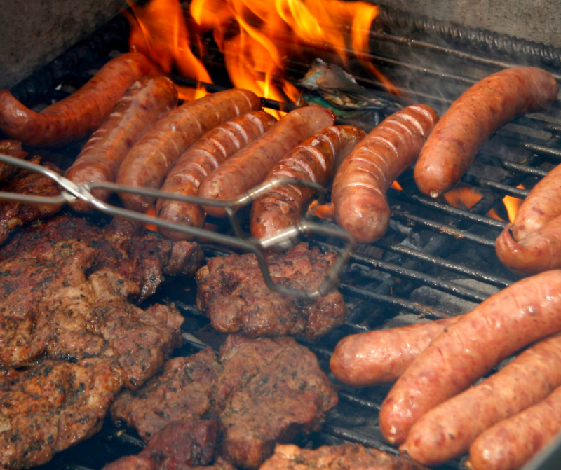 Saucisses et steaks hachés sur barbecue en flammes